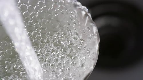 Close up of a running dripping tap. Water flowing and bubbling. Tap water silver kitchen fixtures,