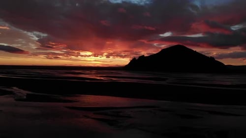 Island-Drohne nach Sonnenuntergang über einem Fluss mit wunderschönen farbigen Wolken und einem Berg rückwärts aufgenommen