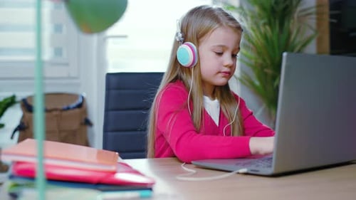 Girl in Headphones Using Laptop at Desk
