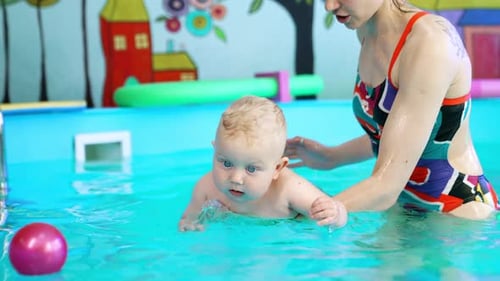 Infant Swimming With Caregiver in Bright Indoor Pool