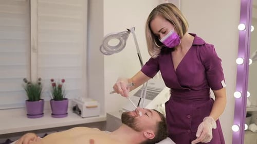 Woman Applying Wax to Man's Face in Spa