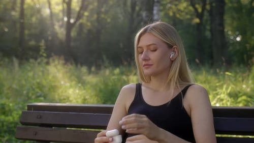 Slender Young Woman in Black Top Put Wireless Headphones and Listen to Podcast or Music