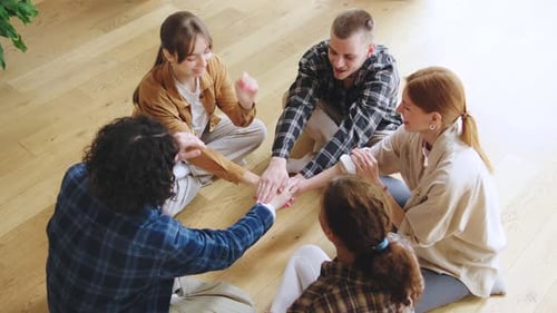 Smiling Young Adults Stacking Hands in Team Circle