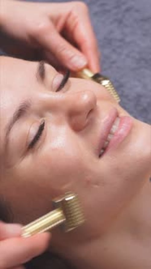 Woman Receiving Facial Massage with Gold Rollers