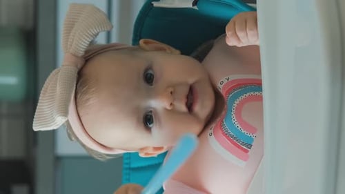 Baby Puts Spoon in Mouth in High Chair
