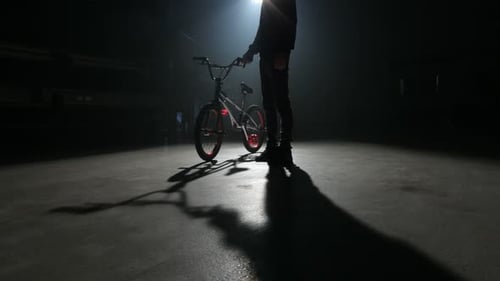 Young bmx rider performs extreme stunts in an abandoned dark warehouse