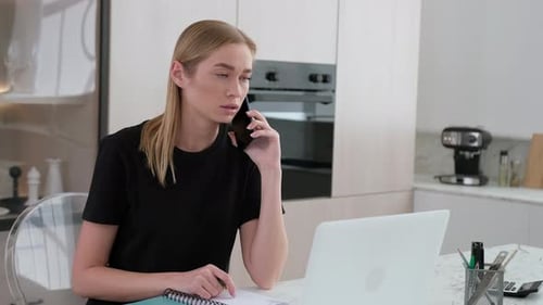 Woman Talking on Phone, Working on Laptop at Home