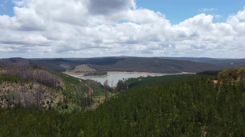Aerial Drone View of Serene Lake Amidst Hills, Mountains, and Lush Forest