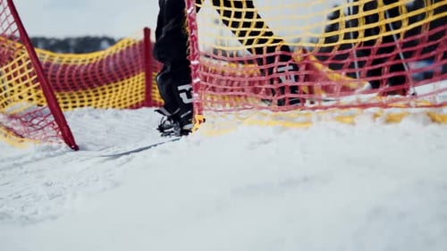 Nahaufnahme einer Person in gelber Jacke beim Snowboarden von einem verschneiten Berg in Zeitlupe.