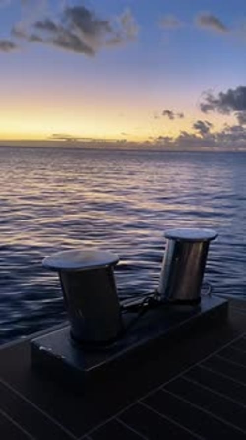 Vertical phone footage of a large stainless steel yacht cleat with an ocean sunset in the background