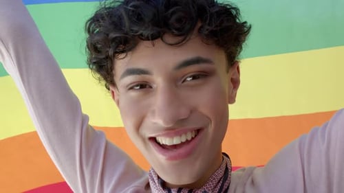 Smiling Young Adult Holding Pride Flag