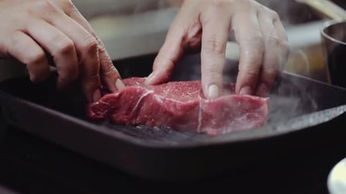 CLOSE UP: Putting steak on BBQ grill pan, pressing steak on a BBQ grill pan.
