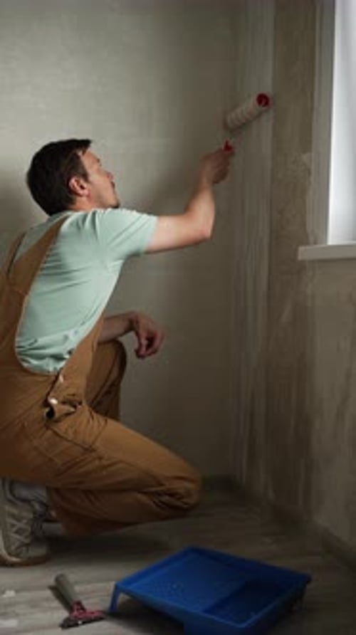 Professional Builder Stripping Worn Wallpaper Preparing Wall Surface for Renovation Using