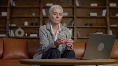 Serious Senior Woman Counting Cash at Office