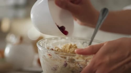 Bakery. Mature woman in loungewear carefully preparing cookies with berries in the kitchen at home