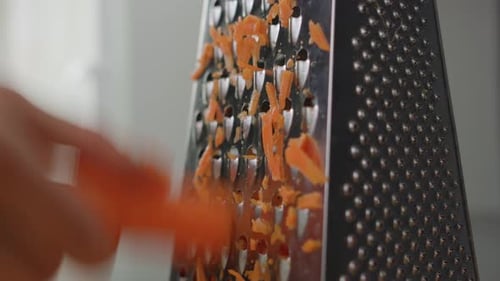 Man shredding a carrot with a grater. Cooking. Close up