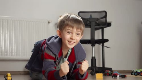 Smiling Child Plays with Toy Cars Indoors