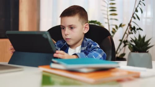 Junge sitzt am Schreibtisch zu Hause und nutzt digitales Tablet für den Fernunterricht