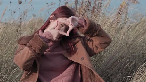 Teen Girl Forms a Frame with Her Hands Mimicking a Photographer's Pose in an Autumn Field