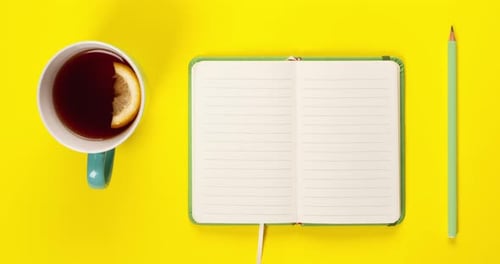 Close Up Video Scale on Mint Tea Cup and Fancy Notebook with Empty or Blank Pages on Bright Yellow
