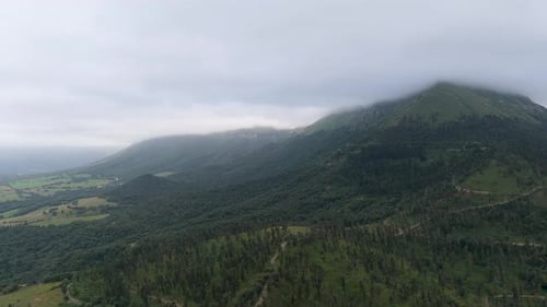 Aerial Drone Flying Over Green Forested Mountains with Clouds