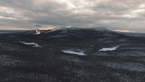 Monochrome Of A Snowy Forest And Mountains Under Clouded Sky In Orford, Quebec, Canada. Aerial Shot