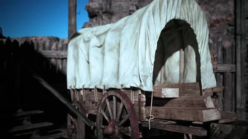 Un vagón de madera cubierto con tela estacionado en un entorno rústico al aire libre