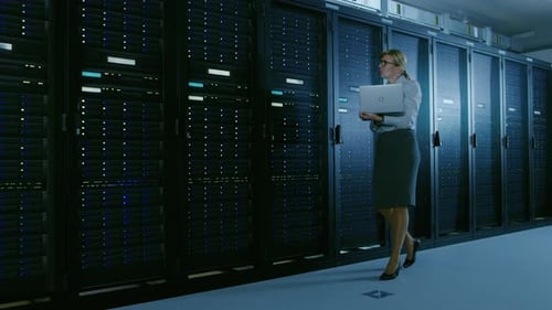 In Data Center Female IT Specialist Walks along the Row of Operational Server Racks, Checking Norma