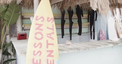 Surfboards and hanging wetsuits in surf rental beach shack, slow motion