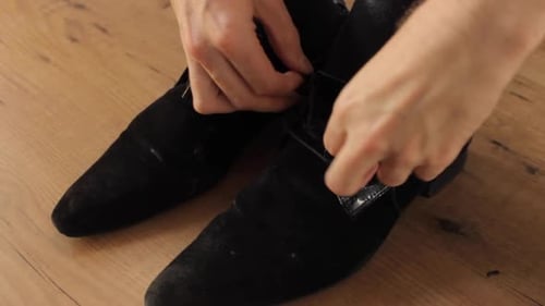 Close up shot of an elegant businessman getting dressed by tying up his shoe laces.