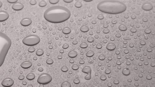 Wasser auf grauen Hintergrund mit Tropfen und Schatten sprühen, Nahaufnahme