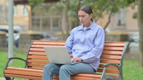 Tense Hispanic Woman Shocked by Loss on Laptop Outdoor