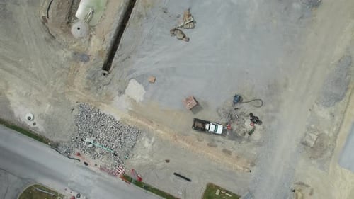 Aerial view of Heavy construction equipment working at the construction site near a lonely road in a