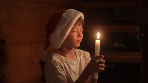 Young Boy Holding Candle in Festive Red Santa Hat