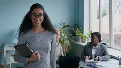 Confident Woman Smiling Holding Tablet in Modern Office