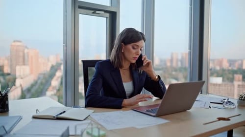 Professional Woman Talking on Phone and Working on Laptop