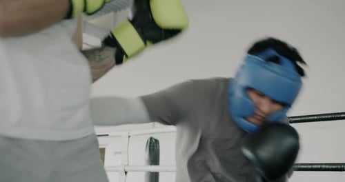 Asian Sportsman Training with Coach Punching Practicing Boxing Moves in Modern Gym