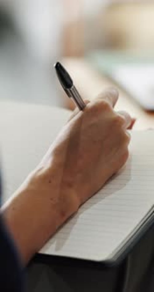 Close-Up of Hand Writing with Pen in Notebook