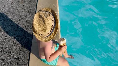 adorable kids siblings brothers on pool edge eating cone ice cream,legs feet playing into water wave