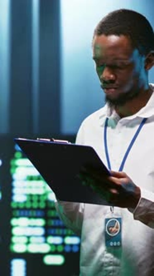 Man Taking Notes Near Computer Screens