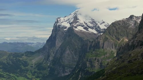 Aerial view of the majestic snow-covered peak of the Eiger in the Bernese Alps, soft clouds wrap