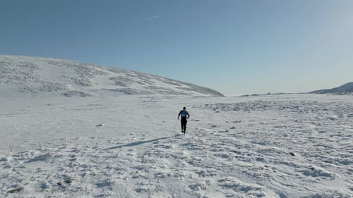 Lone Runner Exercising Across Snowy Winter Field