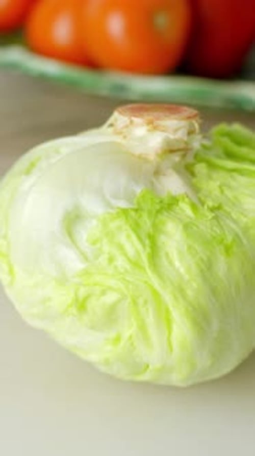 Vertical view closeup at iceberg lettuce, fruits and vegetables displayed at clean kitchen table