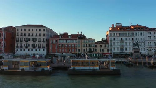 Aerial view flying sideways overlooking houses, gondolas and canals during sunset in Venice in Italy