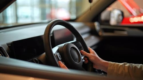 Closeup of Steering Wheel with Unrecognizable Buyer Male Hands on It at Showroom Closeup of Man
