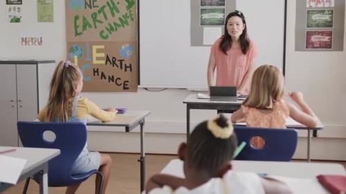 Happy diverse female teacher with tablet teaching schoolgirls in classroom at elementary school