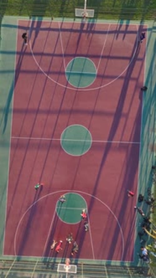 Vertical Video Aerial View Of A Basketball Court With Players Engaging In A Fun Match Under The Open