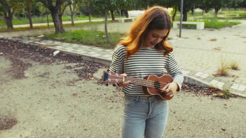 Artist Girl Plays Ukulele Musical Instrument Outside In Park