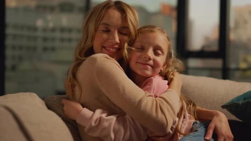 Loving mother and daughter embrace on the couch