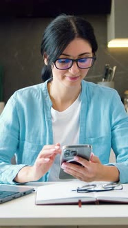 Woman Uses Phone at Desk Indoors Vertical Video